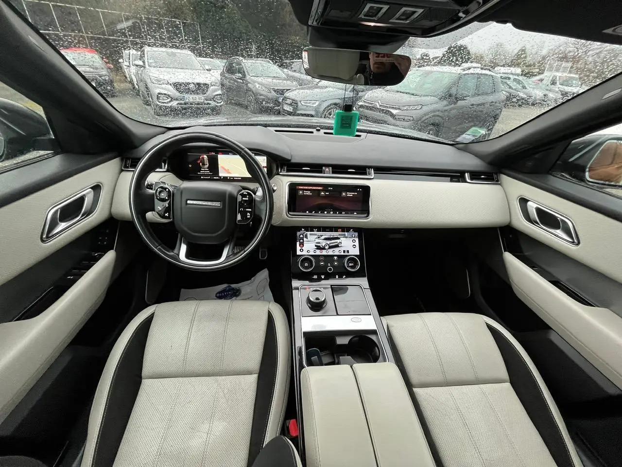 Vue intérieure avant du Range Rover Velar 2017, sièges cuir clair, tableau de bord moderne avec double écran tactile.