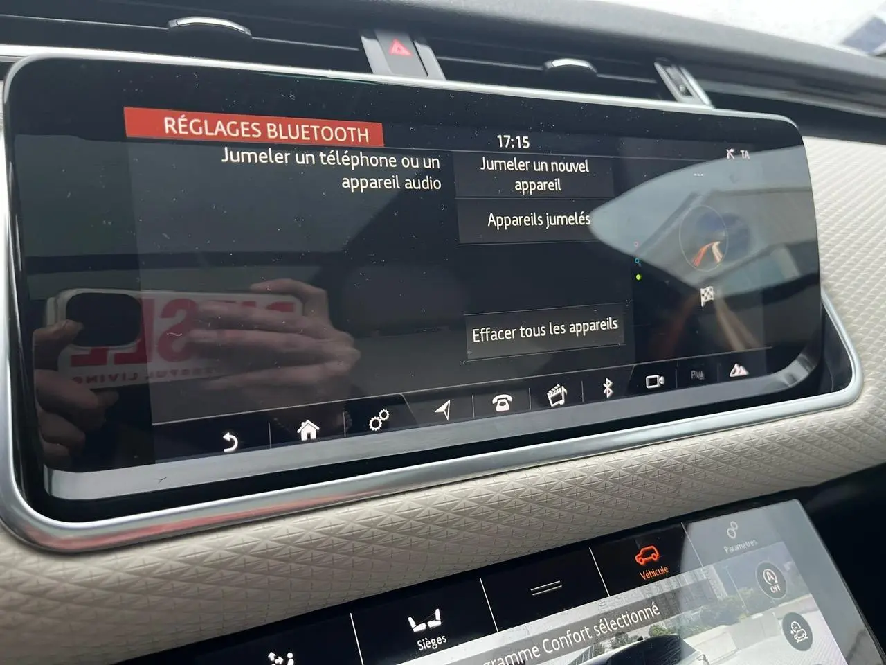 Vue rapprochée de l’écran tactile central du Range Rover Velar gris ammonite, affichant les réglages Bluetooth et options véhicule.