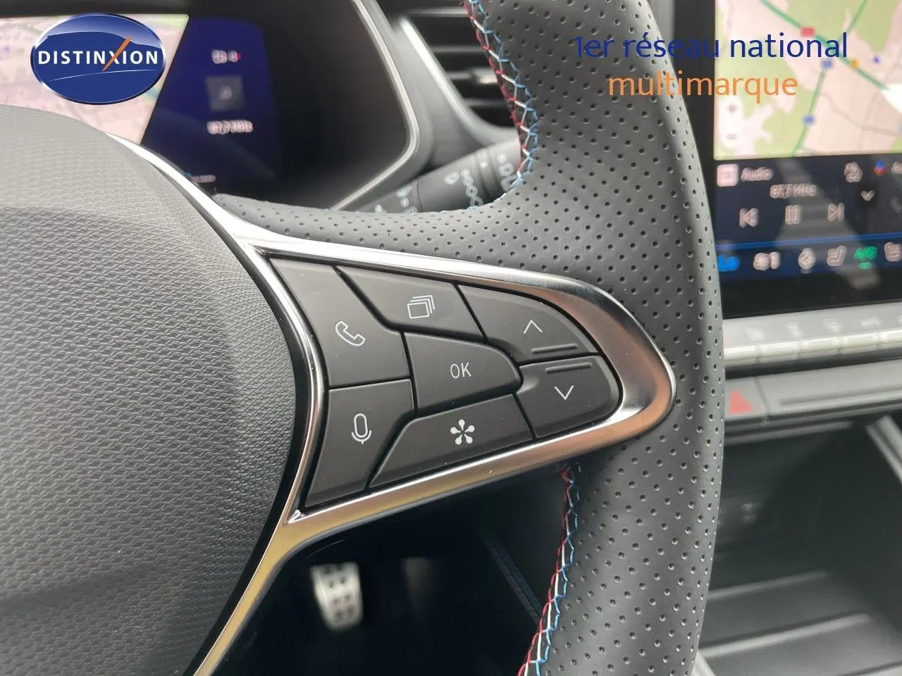 Gros plan sur le volant perforé avec commandes intégrées et coutures tricolores du Renault Symbioz 2026, intérieur noir.