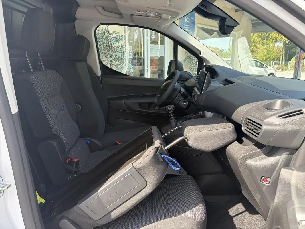 Vue intérieure côté conducteur du Peugeot Partner blanc 2026, montrant les sièges, volant multifonctions et tableau de bord.