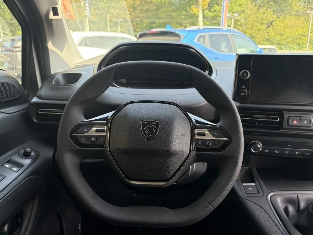 Vue intérieure centrée sur le volant cuir multifonctions du Peugeot Partner blanc avec tableau de bord et écran tactile.