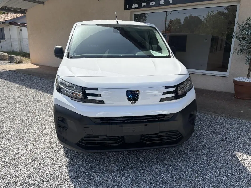 Vue de face d’un Peugeot Partner blanc 2026 avec pare-chocs noir et logo Peugeot central bien visible.