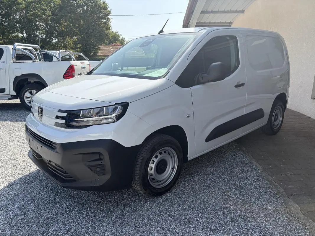 Vue 3/4 avant droit d’un Peugeot Partner blanc 2026, fourgon diesel avec pare-chocs et protections latérales noires.