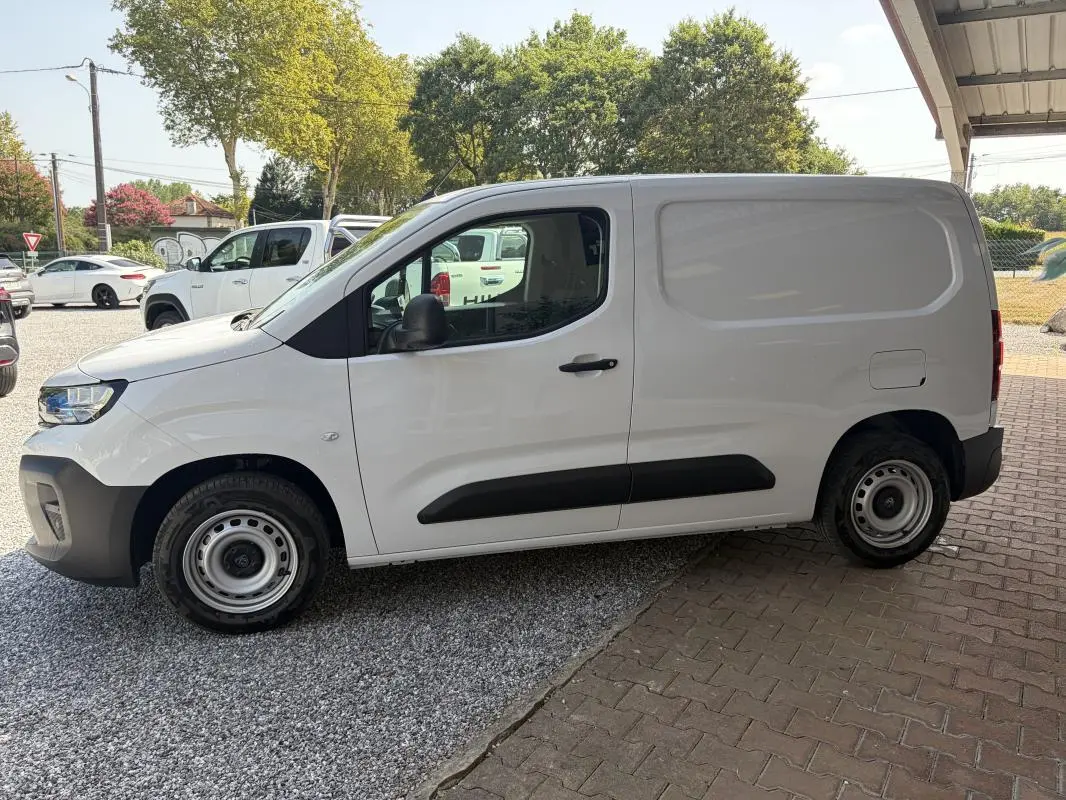 Vue de profil côté gauche d’un Peugeot Partner blanc utilitaire avec porte latérale pleine et jantes acier.