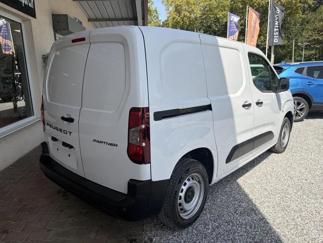 Peugeot Partner blanc en vue 3/4 arrière droit, fourgon utilitaire avec portes arrière battantes et protections latérales noires.