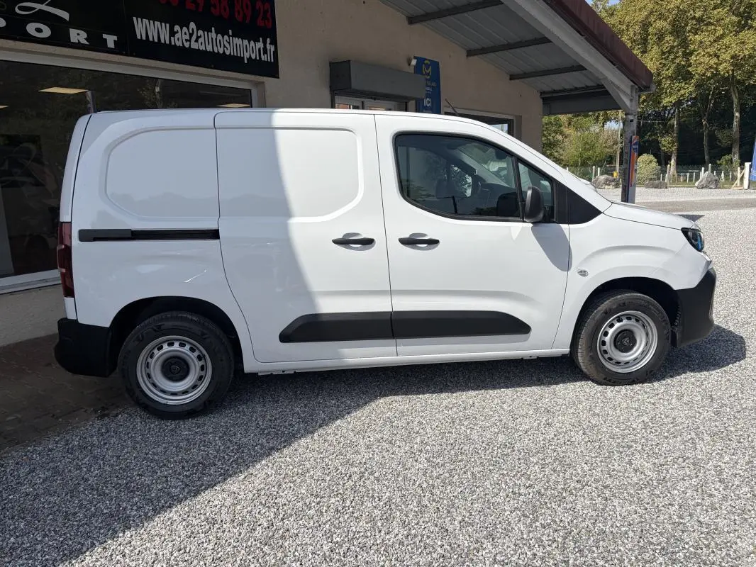 Vue de profil côté droit d’un Peugeot Partner blanc utilitaire avec portes latérales et jantes acier.