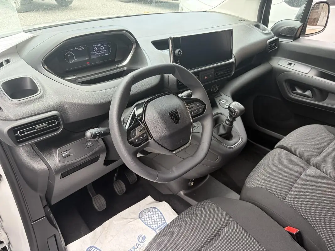 Vue intérieure côté conducteur du Peugeot Partner 2026, montrant le volant multifonctions, levier de vitesse manuel et écran tactile central.