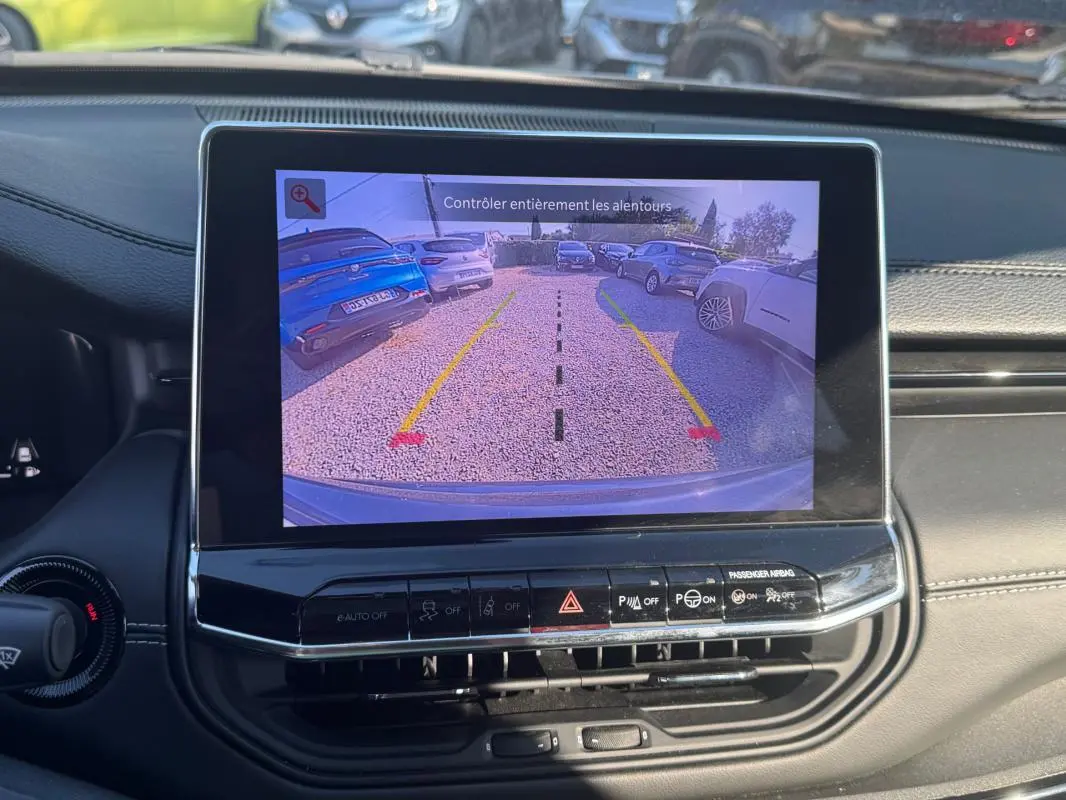 Écran tactile intérieur du Jeep Compass 2025 montrant la caméra de recul avec vue arrière sur un parking.