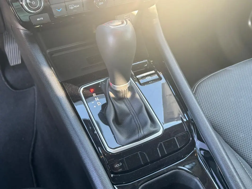 Gros plan sur la console centrale noire du Jeep Compass 2025 avec levier de vitesse automatique et siège gris perforé.