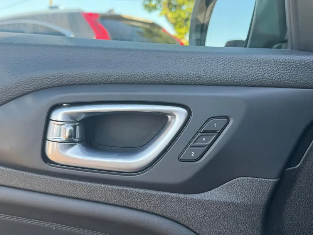 Poignée intérieure de porte côté gauche du Jeep Compass bleu 2025 avec boutons de mémoire des sièges.