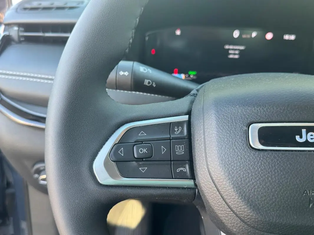 Gros plan sur le volant noir du Jeep Compass 2025, avec commandes intégrées et logo Jeep visible au centre.