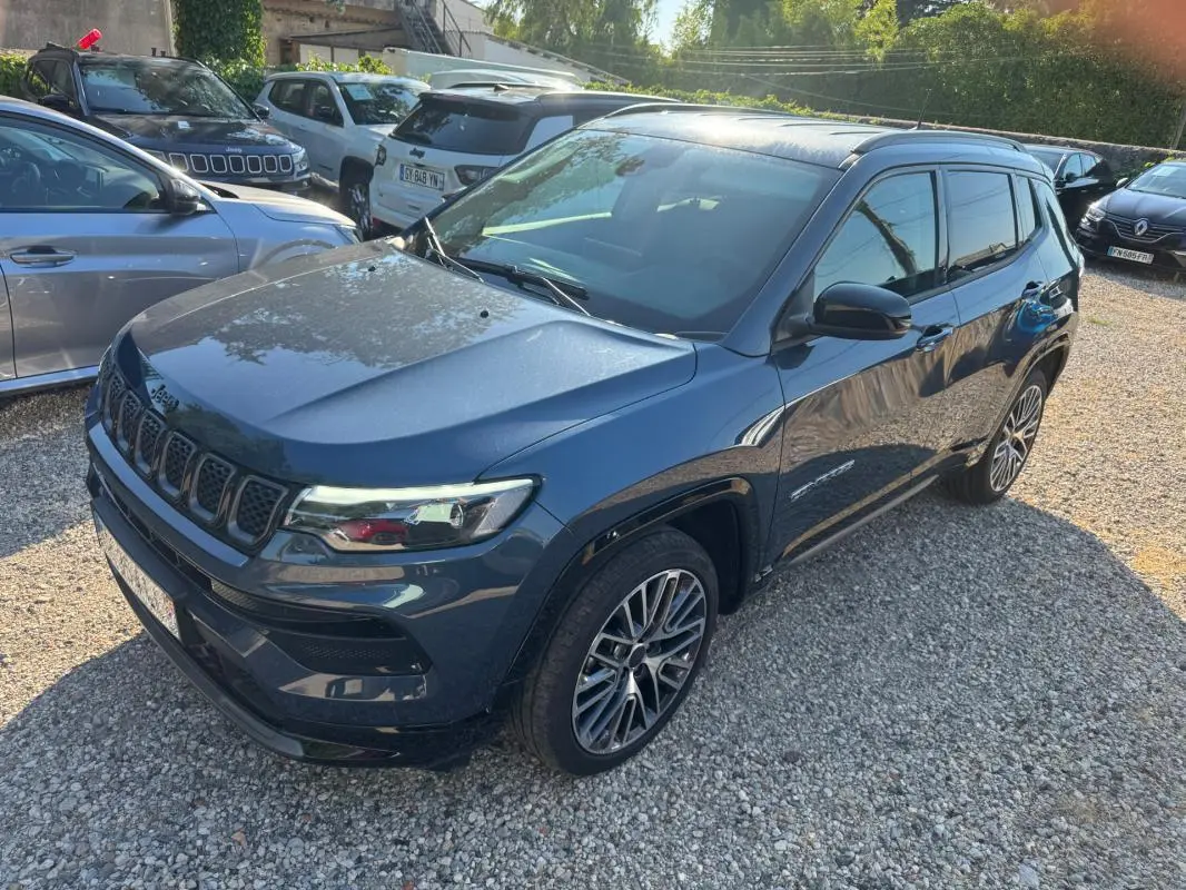 Jeep Compass bleu en vue 3/4 avant droit, avec jantes alliage 19 pouces et barres de toit visibles.