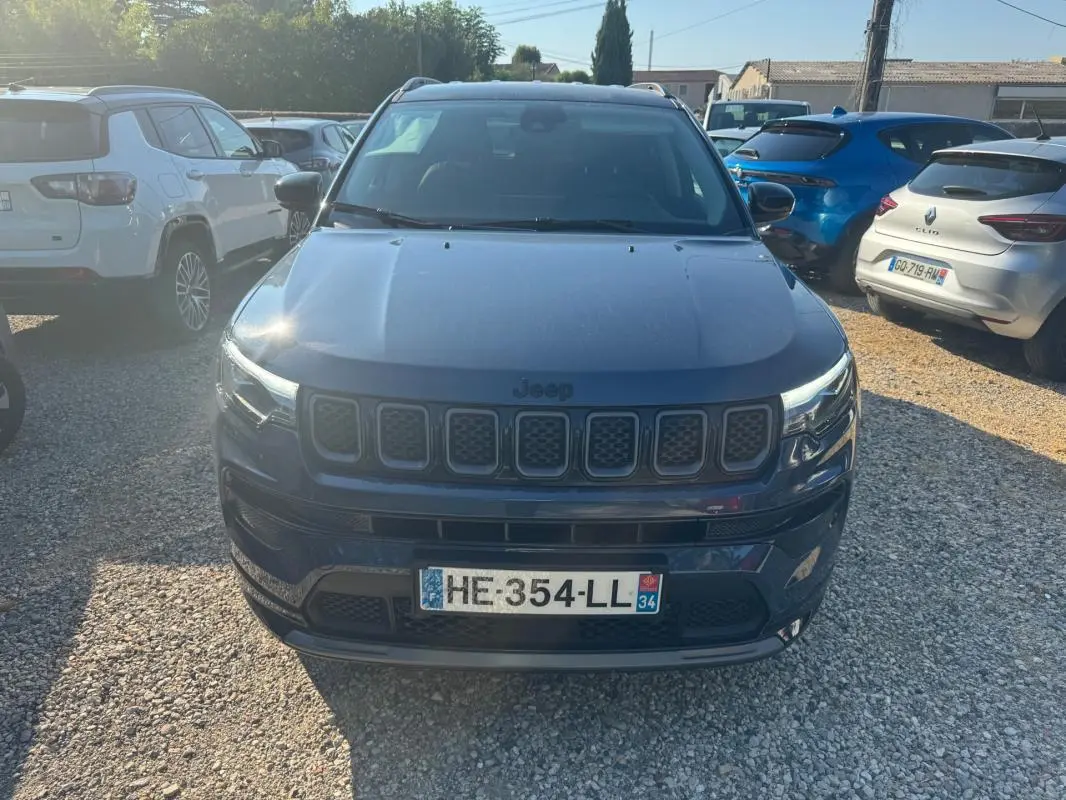 Vue avant d'un Jeep Compass bleu 2025 avec calandre caractéristique et barres de toit visibles en extérieur.