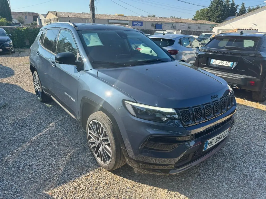 Jeep Compass bleu vue 3/4 avant droit, avec jantes alliage 19 pouces et barres de toit visibles.