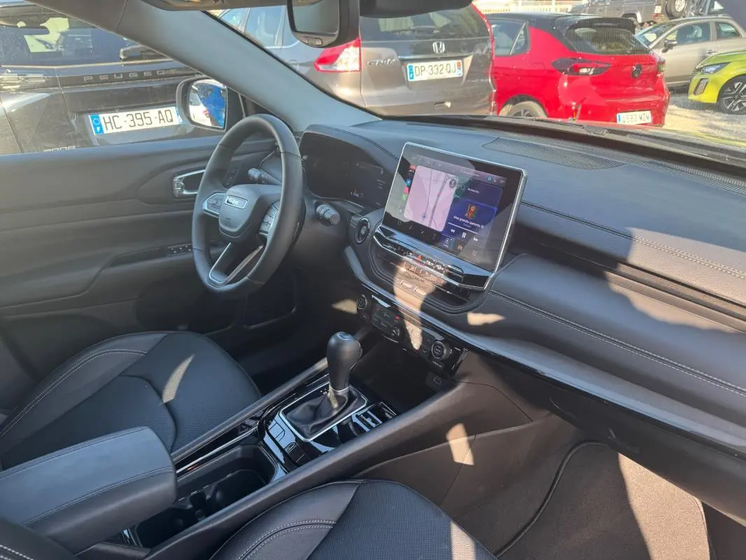 Intérieur avant droit du Jeep Compass bleu 2025, montrant tableau de bord moderne et écran tactile central.