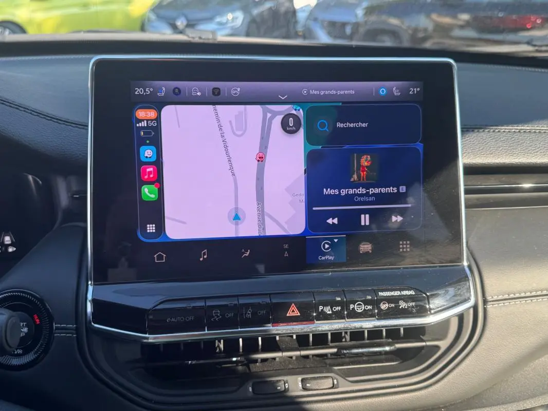 Écran tactile central du Jeep Compass 2025 montrant la navigation et la musique, avec tableau de bord noir en arrière-plan.