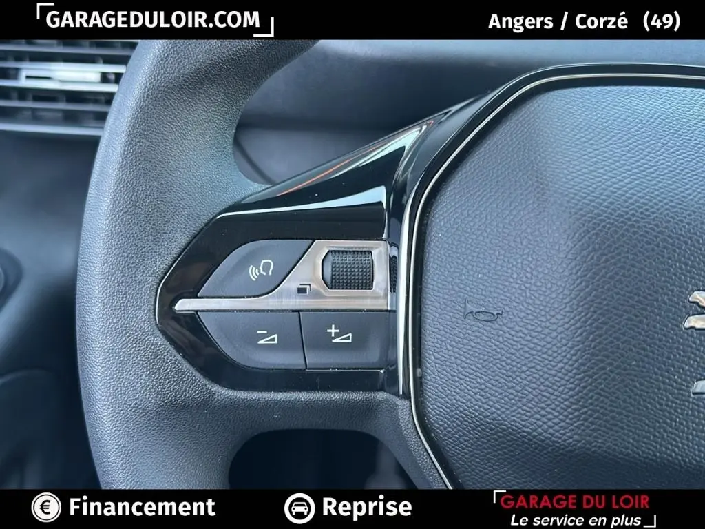 Gros plan sur les commandes gauche du volant noir du Peugeot Rifter 2024, avec boutons de volume et fonction vocale.