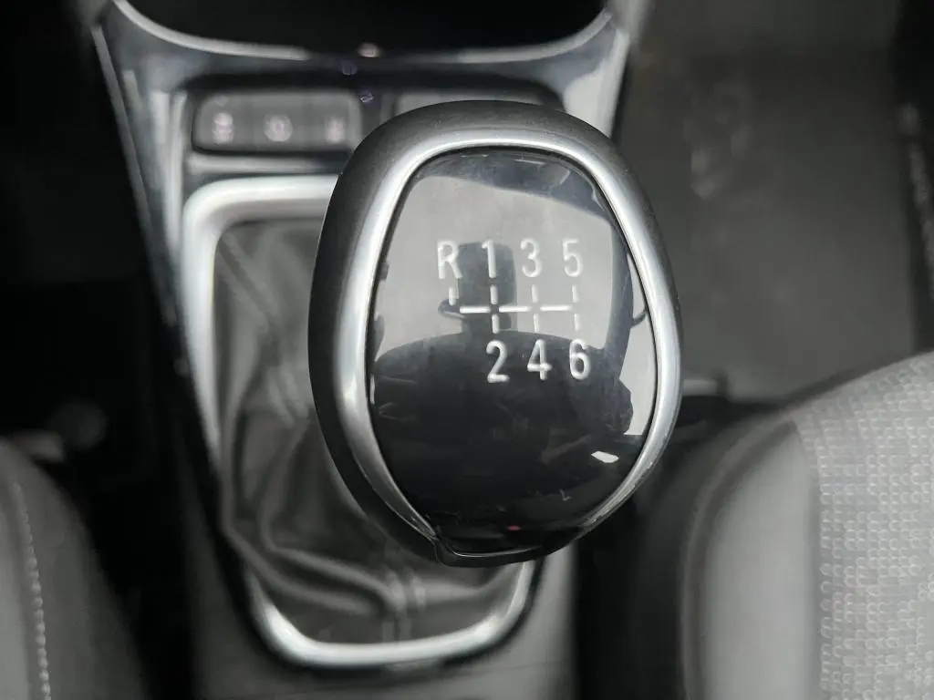 Gros plan sur le levier de vitesses manuel noir brillant de l'Opel Crossland X 1.2i Turbo, intérieur sombre.