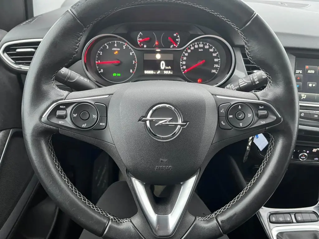 Vue rapprochée du volant en cuir noir de l'Opel Crossland X 2021 avec commandes intégrées et tableau de bord digital.
