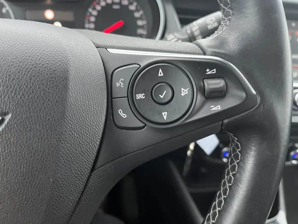 Gros plan sur les commandes au volant en cuir noir de l'Opel Crossland X 2021, avec boutons multifonctions visibles.
