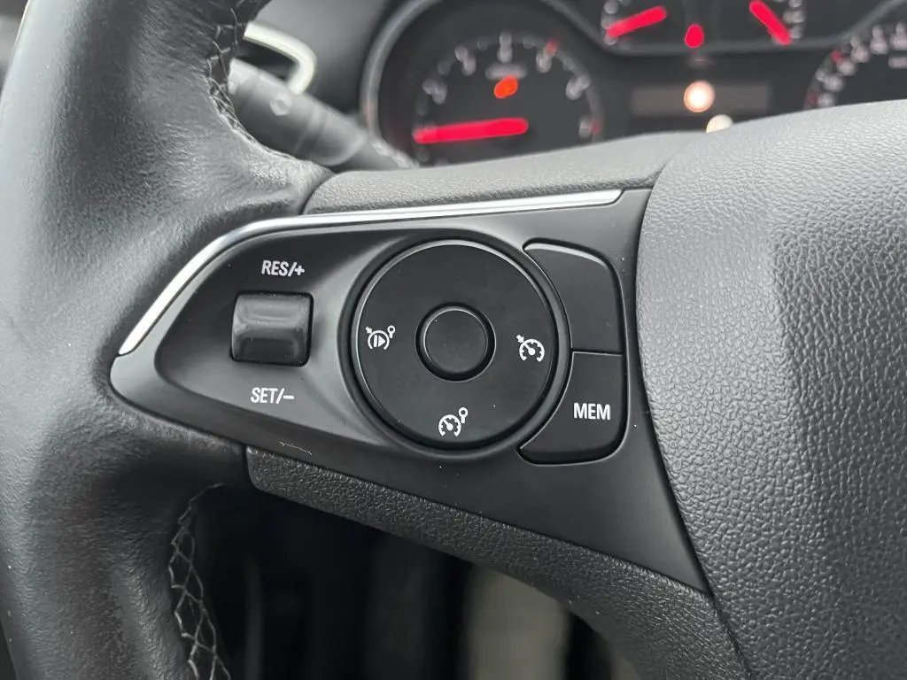 Gros plan sur les commandes de régulateur de vitesse au volant noir de l'Opel Crossland X 2021.