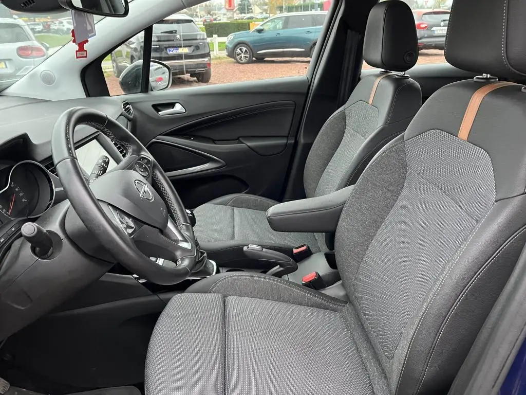 Vue intérieure côté conducteur de l’Opel Crossland X bleu clair 2021, sièges gris avec surpiqûres marron et volant multifonction.