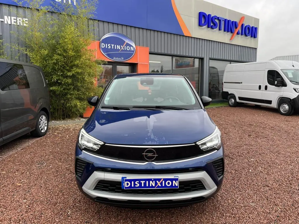 Vue avant d'un Opel Crossland X bleu clair avec toit noir, stationné devant un concessionnaire Distinxion.
