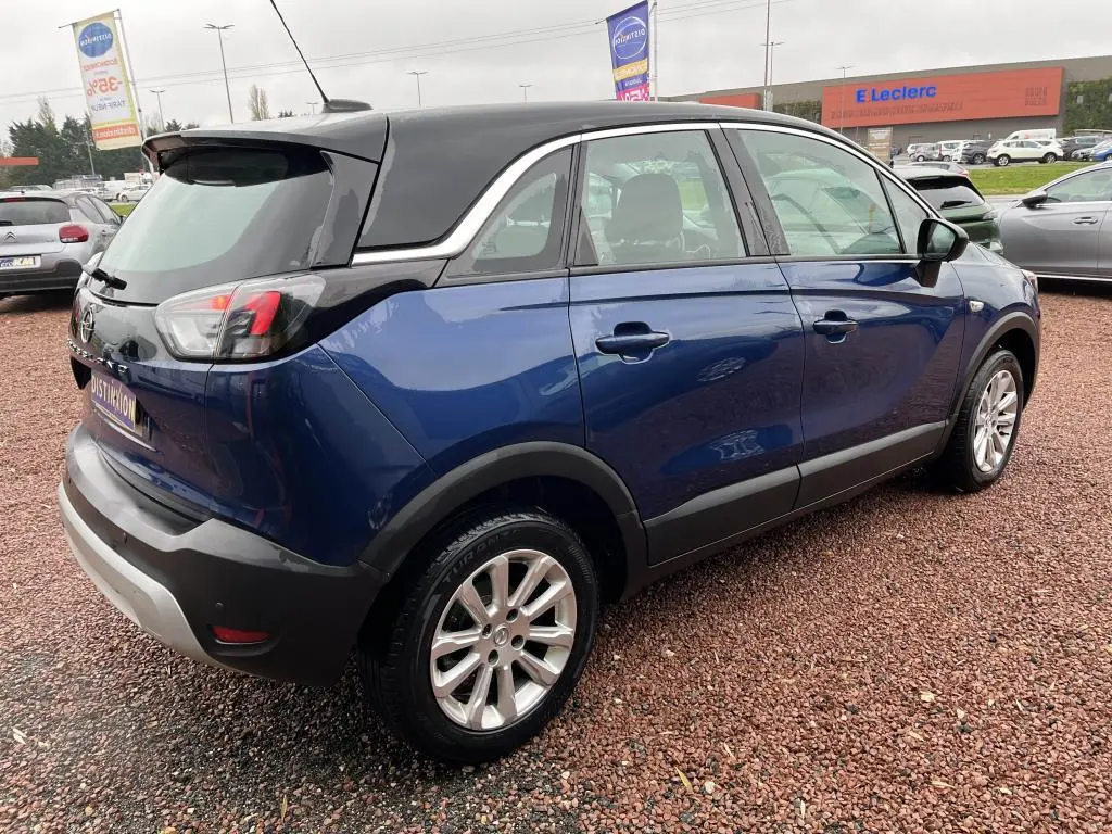 Opel Crossland X bleu clair vue 3/4 arrière droit avec toit noir et jantes alliage sur parking extérieur.