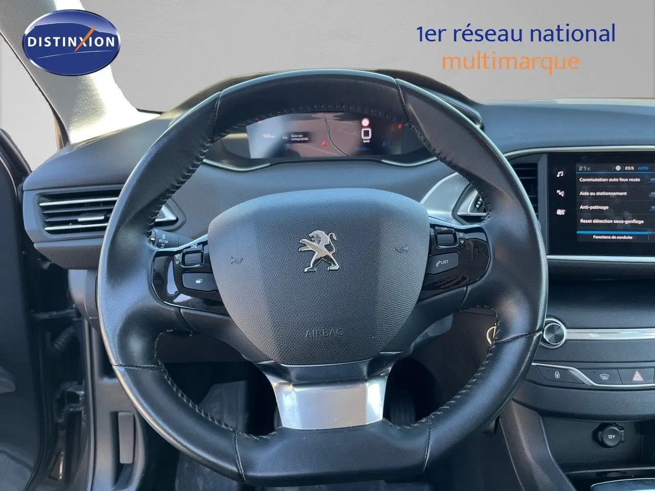 Vue intérieure centrée sur le volant cuir noir de la Peugeot 308 Business 2020 avec tableau de bord digital et écran tactile.