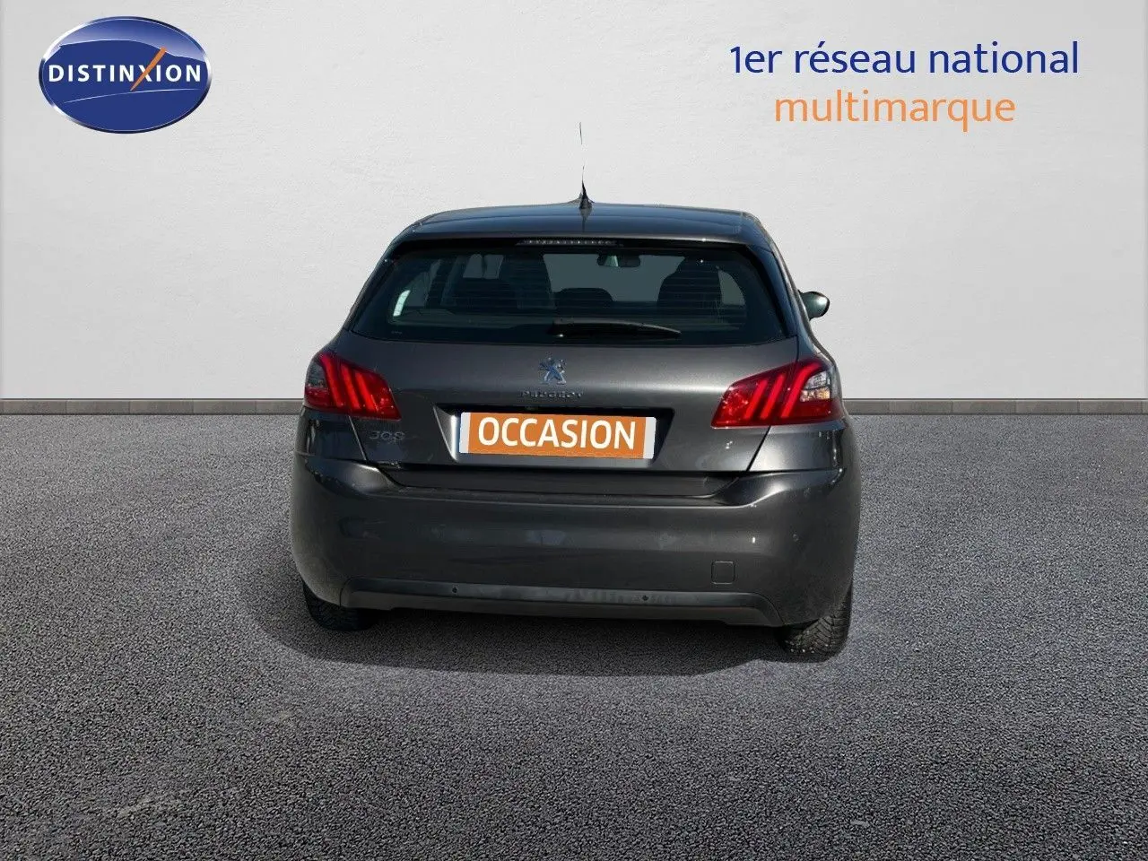 Vue arrière de la Peugeot 308 Business gris foncé de 2020 avec feux arrière allumés et plaque occasion visible.