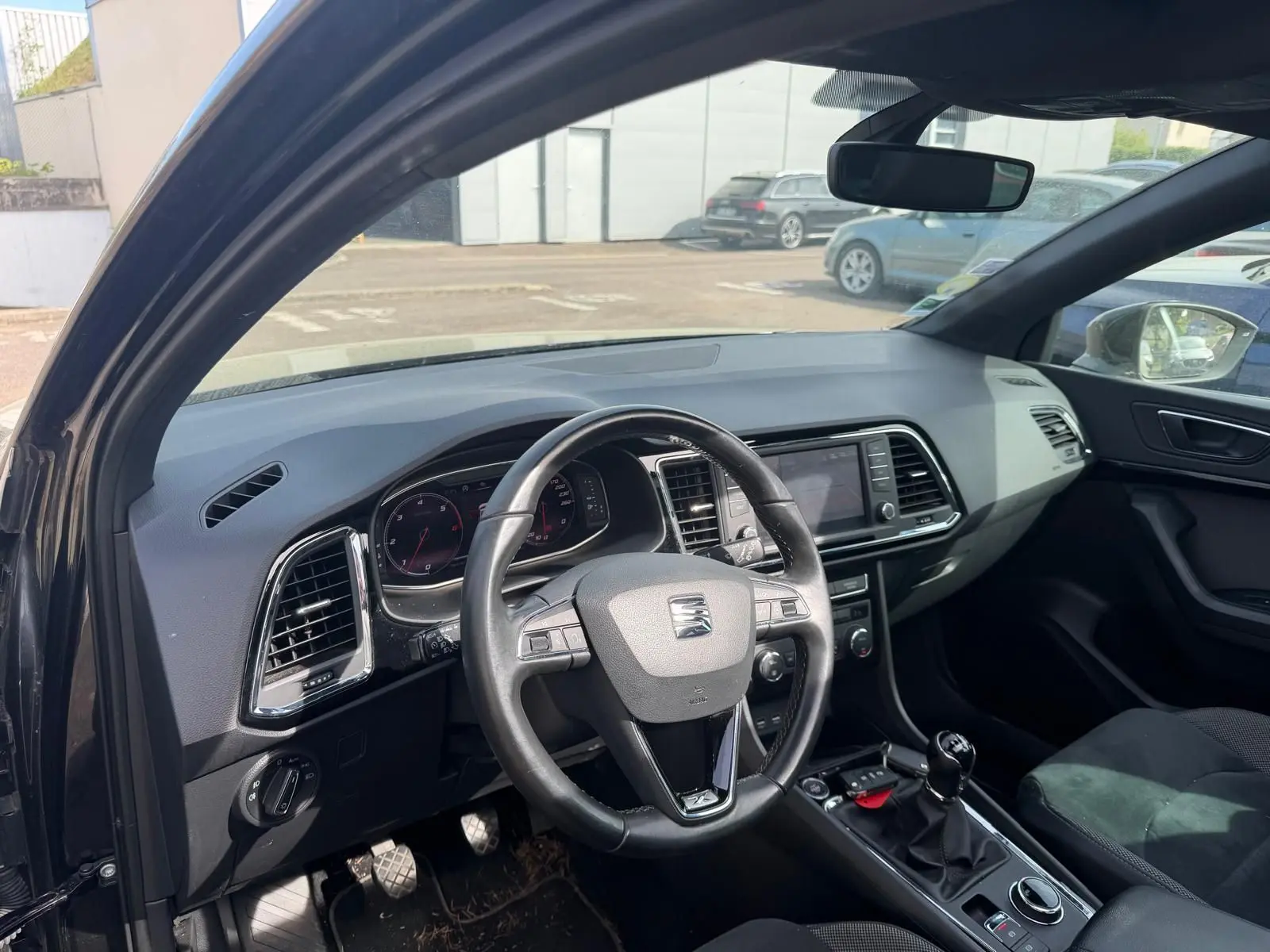 Vue intérieure côté conducteur du SEAT Ateca noir 2019, volant cuir multifonctions et tableau de bord moderne.