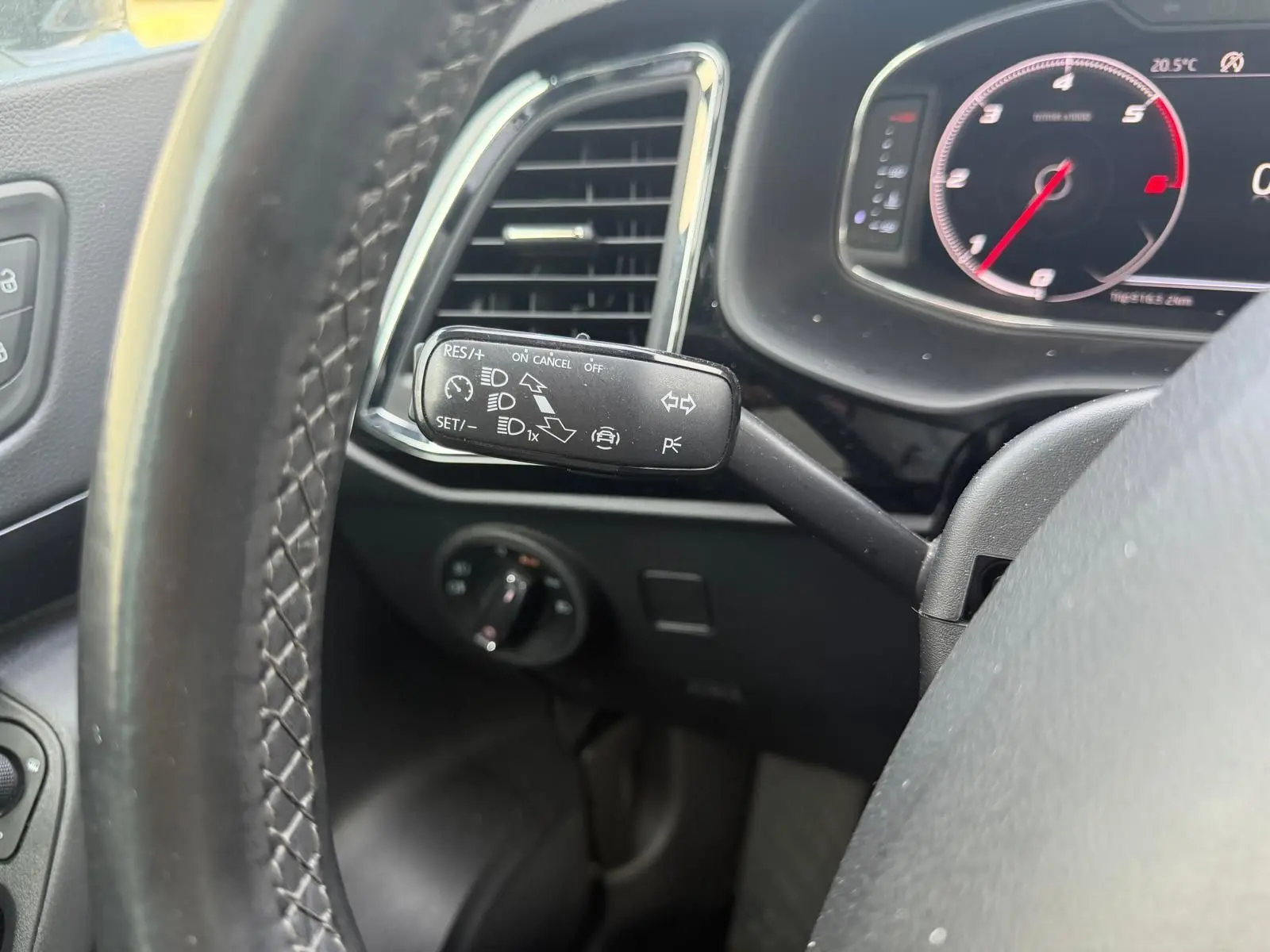 Gros plan sur la manette de régulateur de vitesse à gauche du volant cuir noir du tableau de bord digital du SEAT Ateca noir.