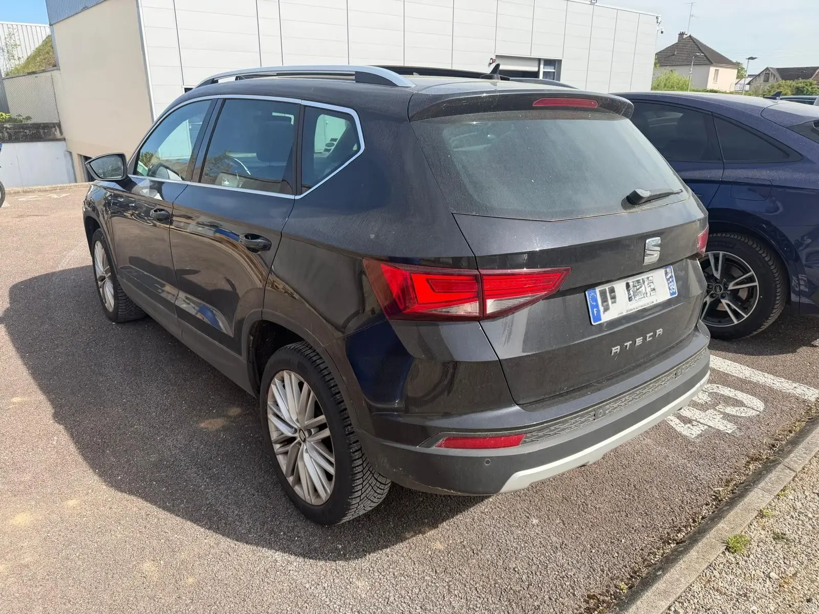 Vue 3/4 arrière droite d'un SEAT Ateca noir avec jantes alliage et feux arrière LED, stationné en extérieur.