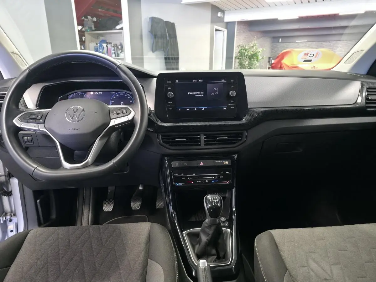 Vue intérieure frontale du Volkswagen T-Cross gris, avec volant multifonction en cuir et écran tactile central.