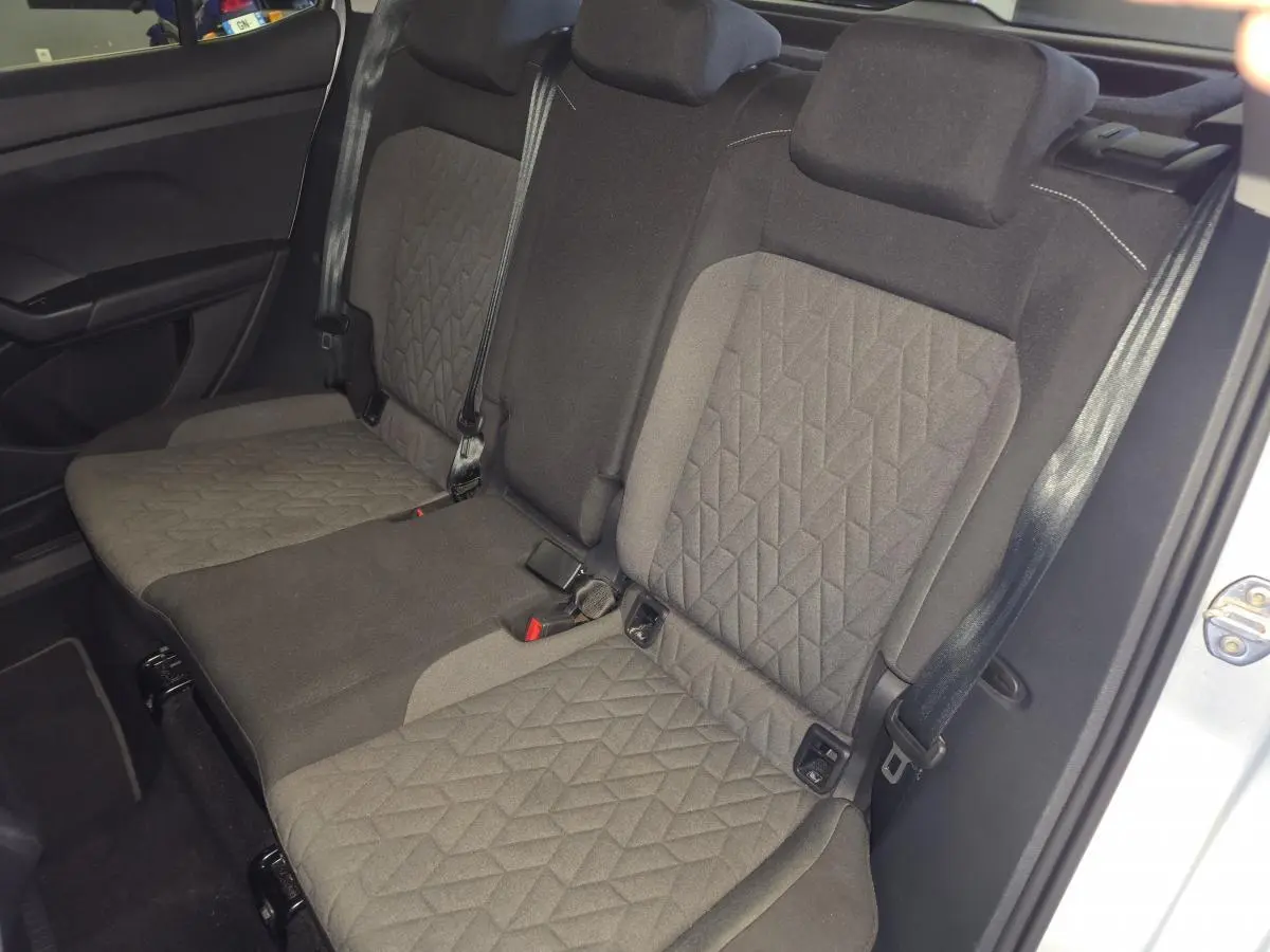 Vue intérieure de la banquette arrière en tissu gris foncé du Volkswagen T-Cross 2025, avec ceintures de sécurité visibles.