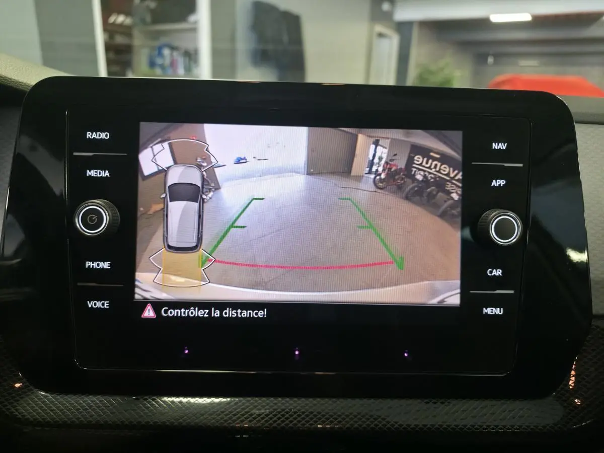 Écran de caméra de recul du Volkswagen T-Cross gris montrant l’arrière avec repères de distance en garage.