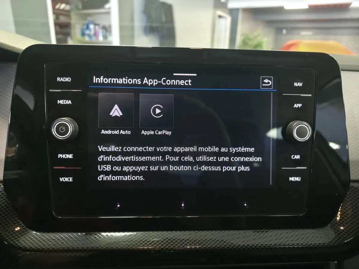 Écran tactile central noir affichant l'interface App-Connect dans l'habitacle d'un Volkswagen T-Cross gris.