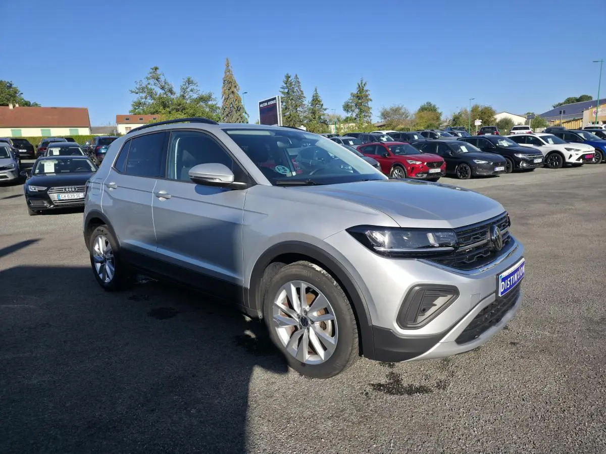 Volkswagen T-Cross gris métallisé en 3/4 avant droit, avec jantes alliage et calandre noire distinctive.