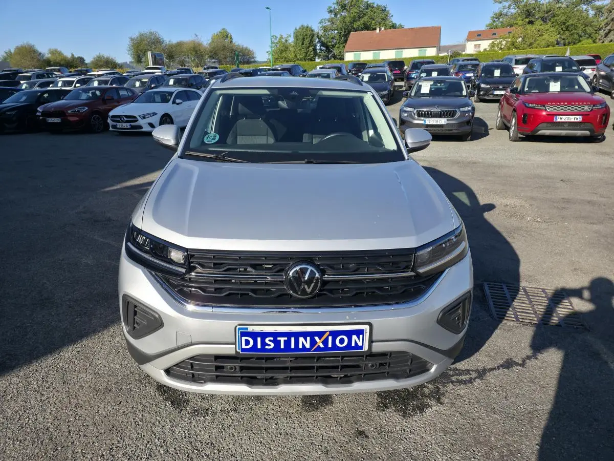 Volkswagen T-Cross gris métallisé vue de face, avec calandre noire et logo VW central bien visible.