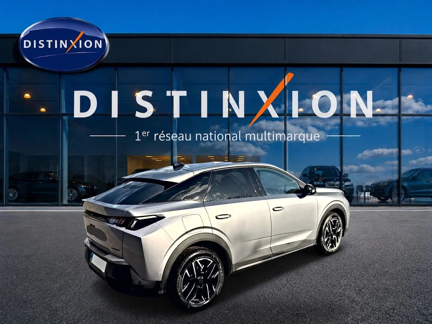 Peugeot 3008 gris artense en 3/4 arrière droit, avec jantes alu noires et toit noir brillant, devant showroom Distinxion.