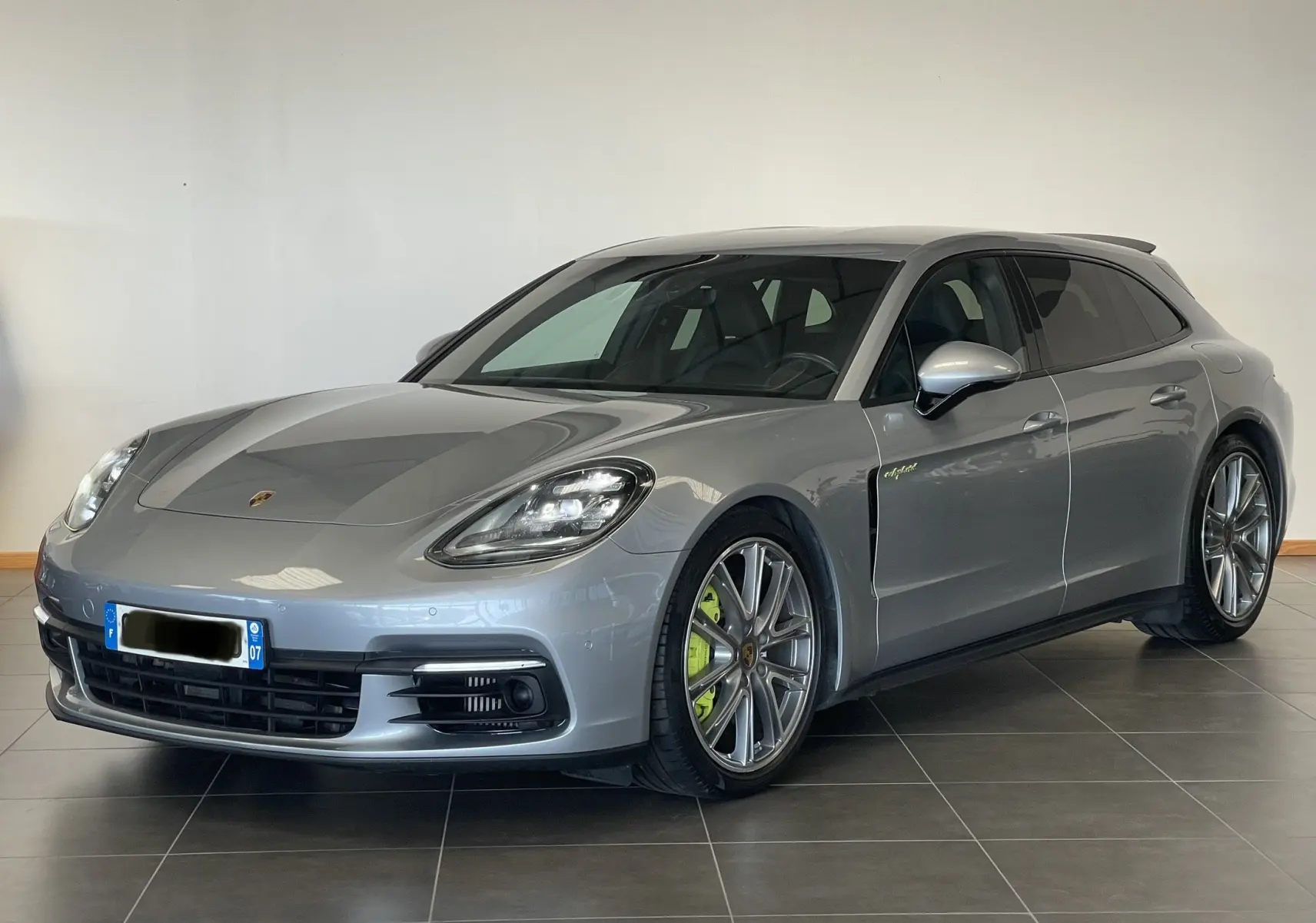 Vue 3/4 avant droite d'une Porsche Panamera Sport Turismo grise de 2018 avec jantes alliage et étriers verts hybrides.