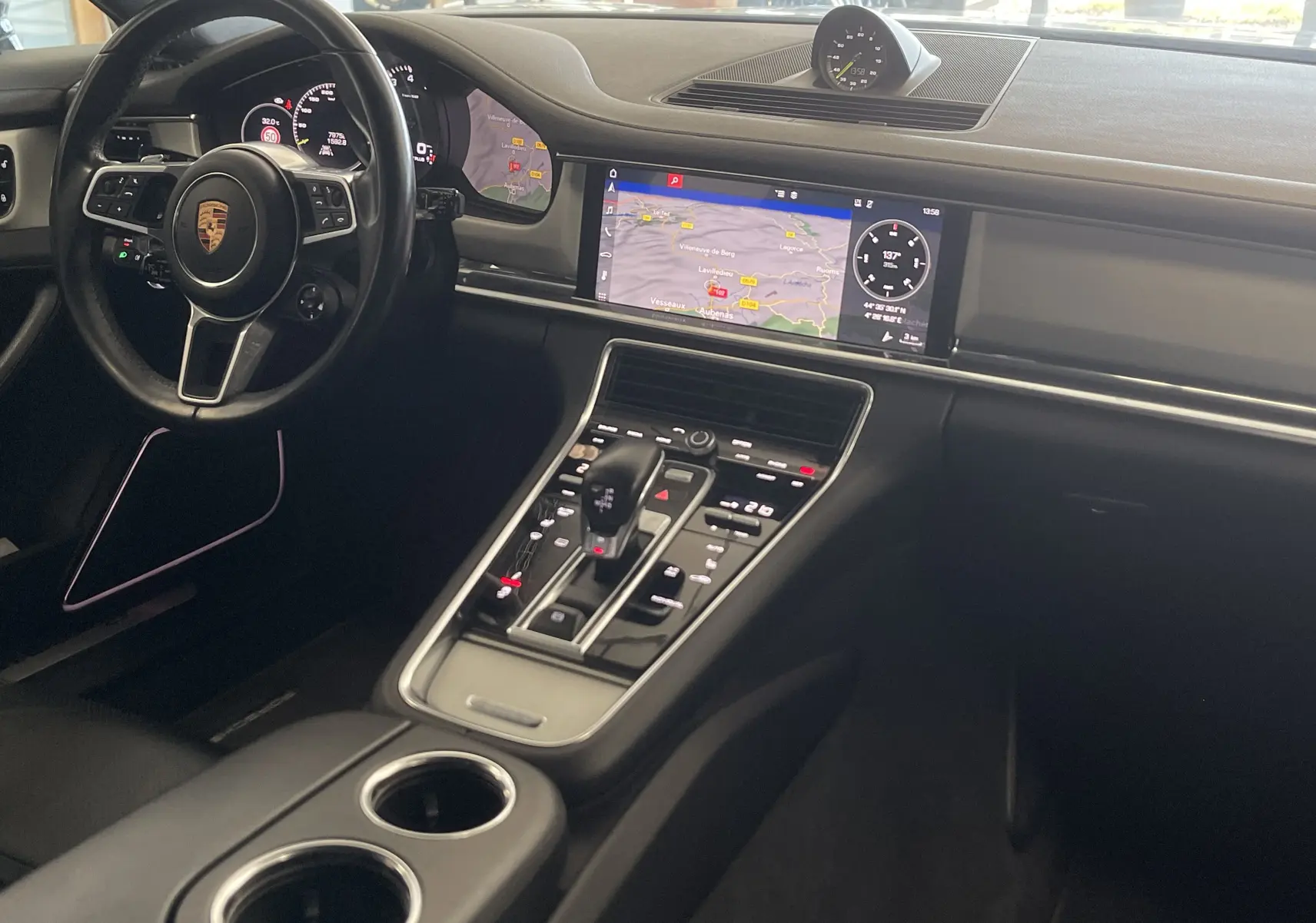 Vue intérieure du tableau de bord et console centrale de la Porsche Panamera Sport Turismo gris, avec écran tactile et volant multifonction.