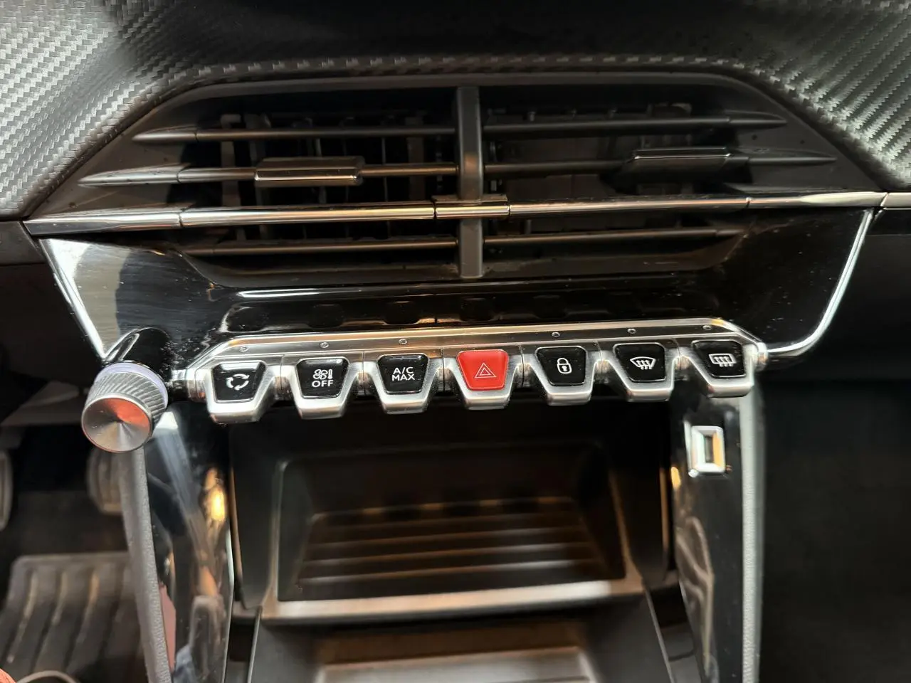 Gros plan sur la rangée de boutons de commande sous la ventilation du tableau de bord d'une Peugeot 208 jaune clair.