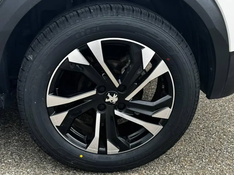 Gros plan sur la jante alu noire et argentée du côté avant droit d'un Peugeot 2008 blanc banquise de 2020.