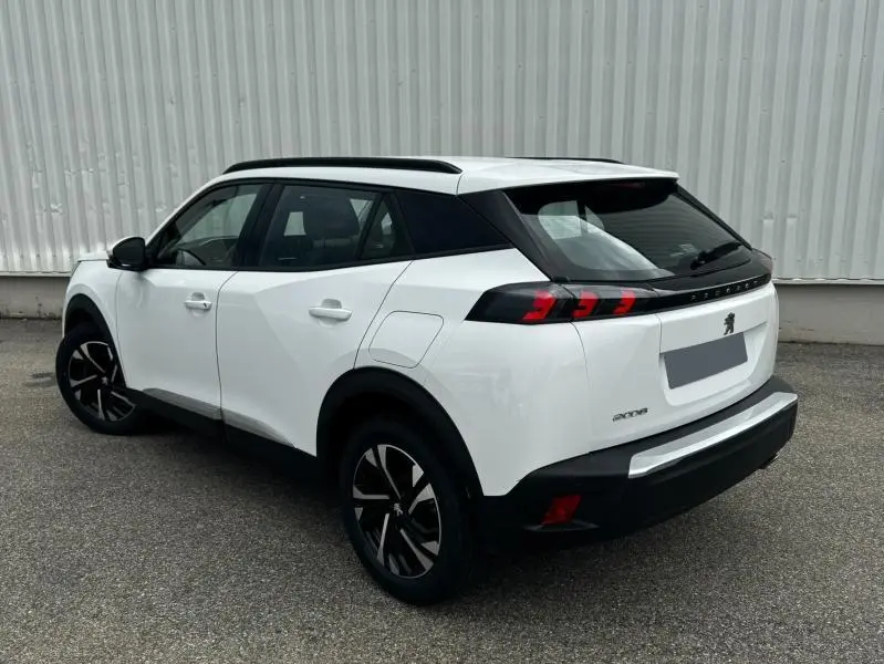 Peugeot 2008 blanc banquise vue 3/4 arrière droit, avec barres de toit et feux arrière LED distinctifs.