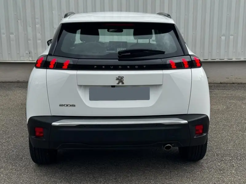 Vue arrière d'un Peugeot 2008 blanc banquise avec feux arrière LED et logo lion central sur hayon noir.
