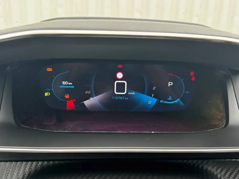 Tableau de bord numérique du Peugeot 2008 blanc banquise, affichant vitesse à 0 km/h et autonomie restante de 60 km.