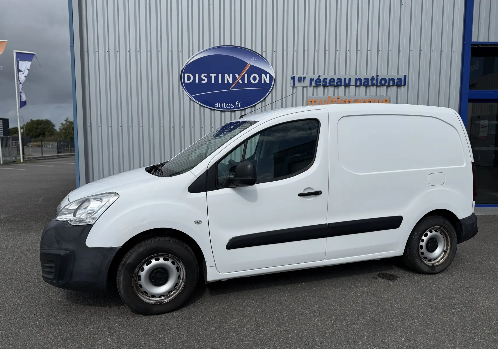 Vue de profil côté gauche d’un utilitaire Peugeot Partner blanc avec protections noires sur les portières.