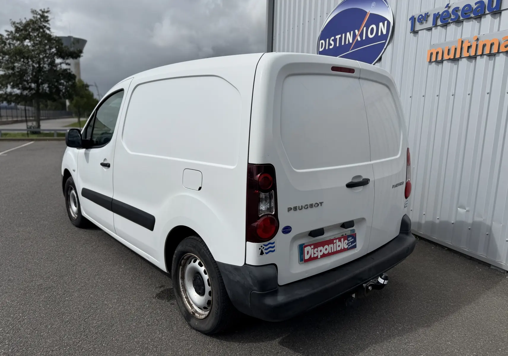 Vue 3/4 arrière droite d’un utilitaire Peugeot Partner blanc de 2017 avec hayon fermé et attelage visible.