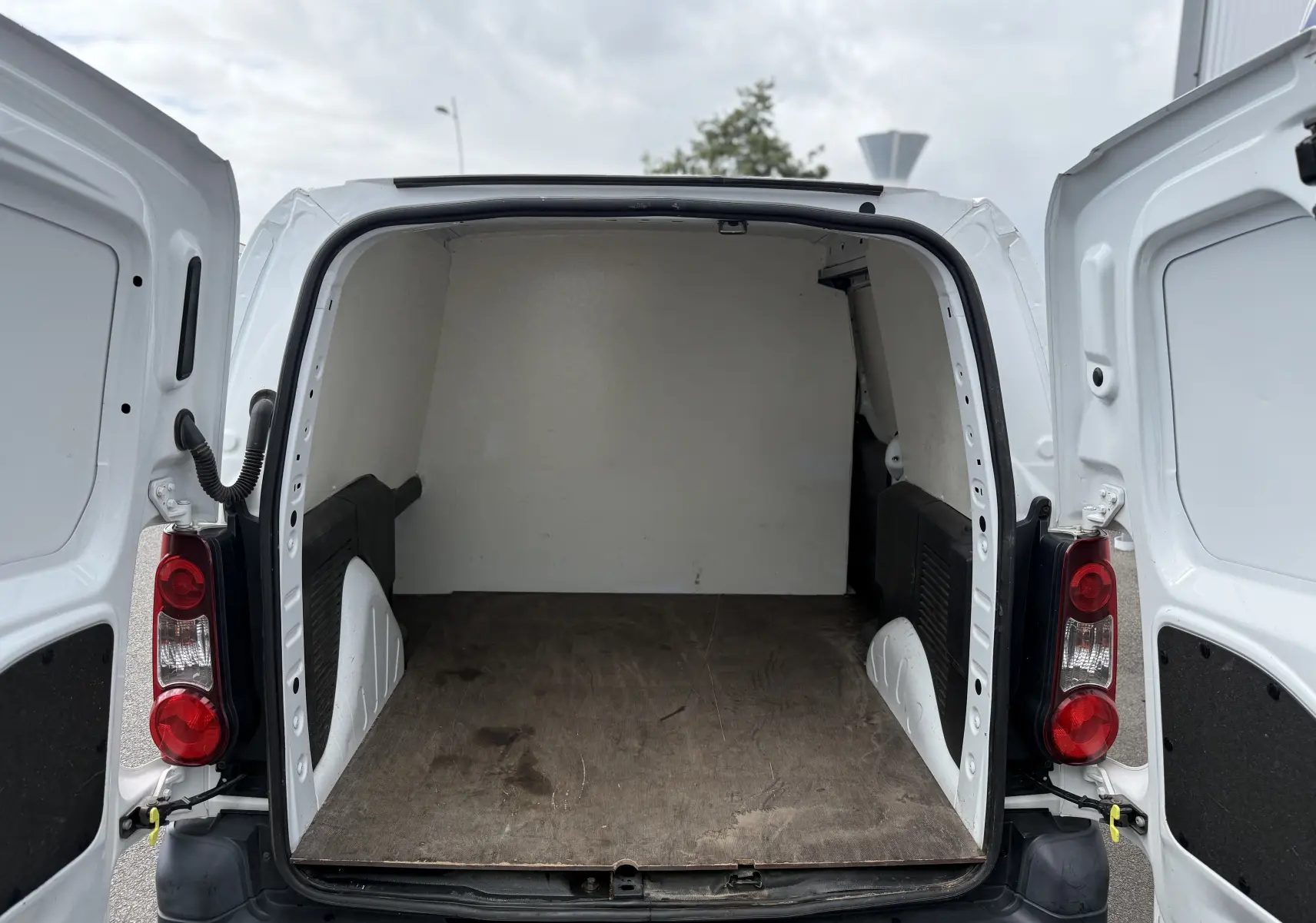 Vue arrière ouverte du Peugeot Partner blanc 2017, montrant l'espace de chargement vide avec plancher en bois.
